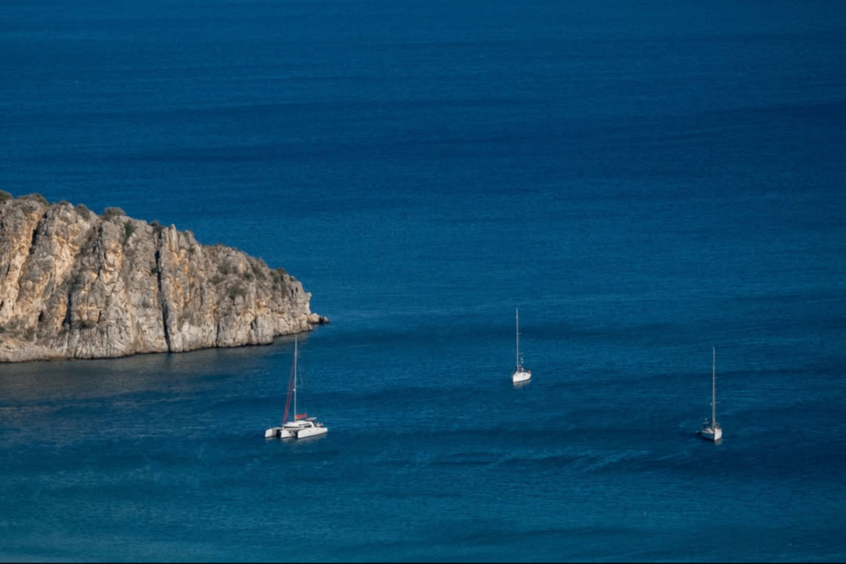 Sailing boats in Tolo bay with Romvi islet behind